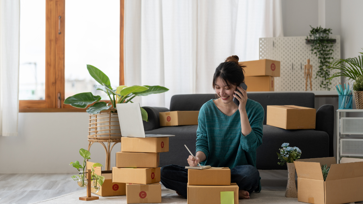 Independent woman work at home use smartphones and laptops for commercial checking, online marketing, packing boxes, SME sellers, concept, e-commerce team, online sales.