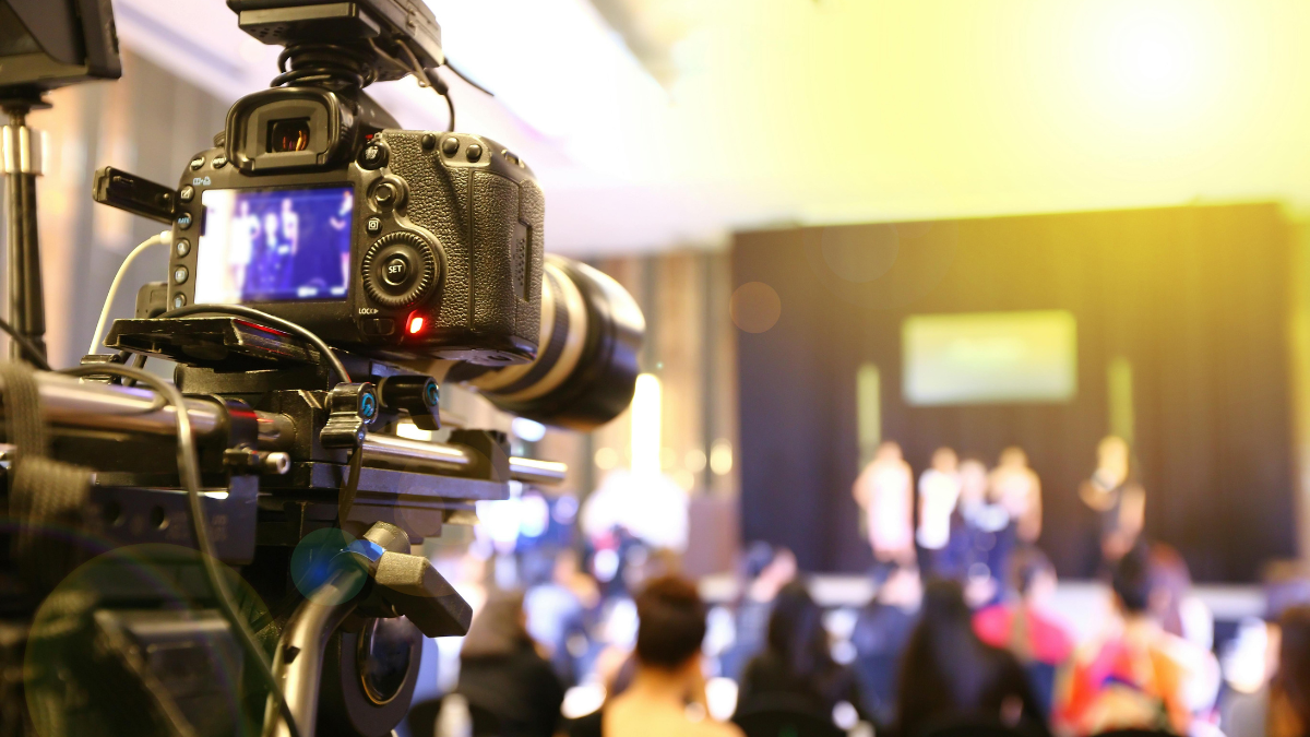 Professional event videography camera capturing a live event audience and stage, representing End-to-End AI Cloud Photography Solutions for seamless event content capture and delivery.