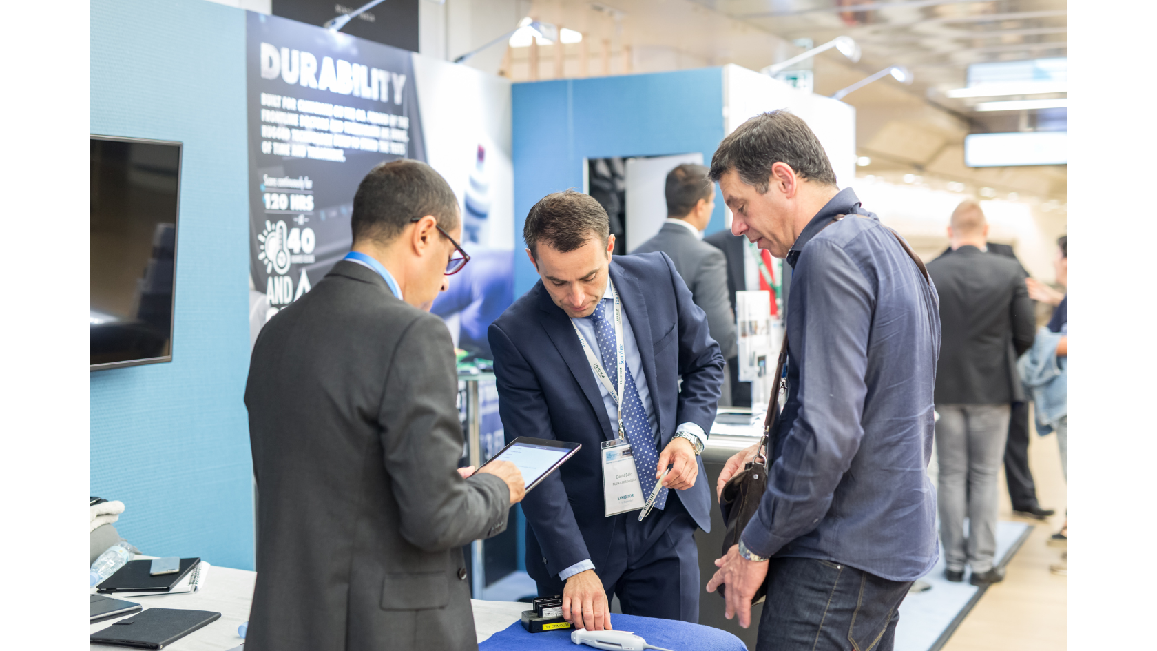 A back-view of a large audience seated in a dimly lit conference hall, watching a speaker panel on stage with a presentation screen, representing the physical scale of events now optimized by AI data analytics.
