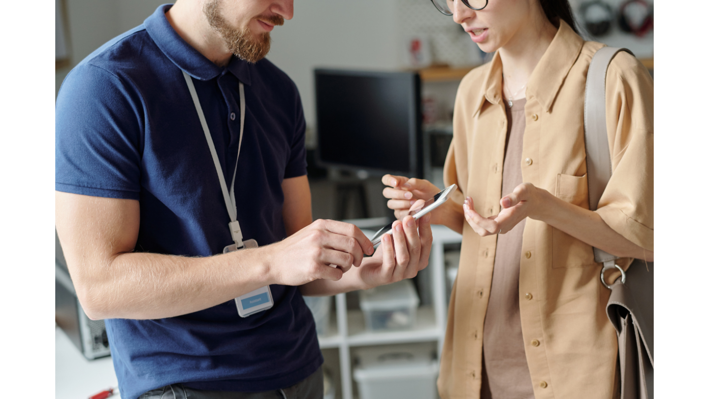 Event staff demonstrating the features of a mobile event app to an attendee on a smartphone.