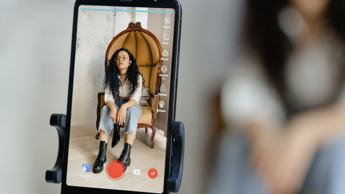 A mobile phone screen shows a live video of a stylish influencer, demonstrating a core element of 'Influencers with Social Ads' strategies.