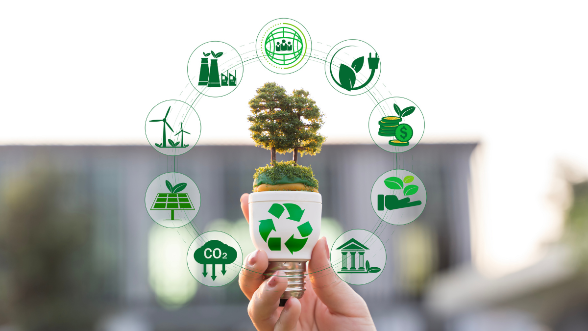 A person’s hand holding a white lightbulb topped with a miniature green tree, symbolizing innovative and bright ideas for environmental conservation. Surrounding the bulb is a circular digital overlay of green icons representing sustainable technology and eco-friendly strategies, including renewable energy (solar and wind), carbon reduction, recycling, and green finance. The image illustrates the integration of technology and nature to achieve a zero-paper, sustainable future for the events industry.