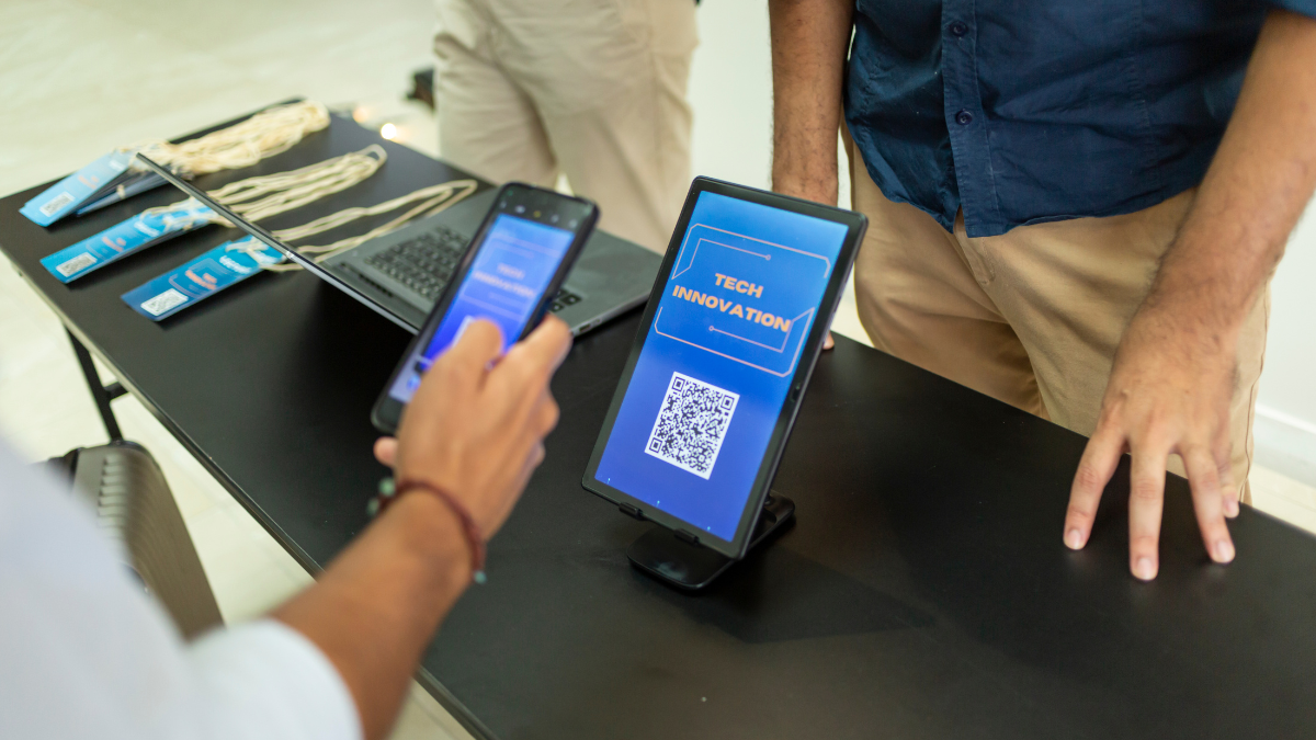 A visitor scans a QR code on a digital check-in tablet at an event registration desk, illustrating a paperless, tech-driven workflow that supports sustainable, zero-paper event strategies.