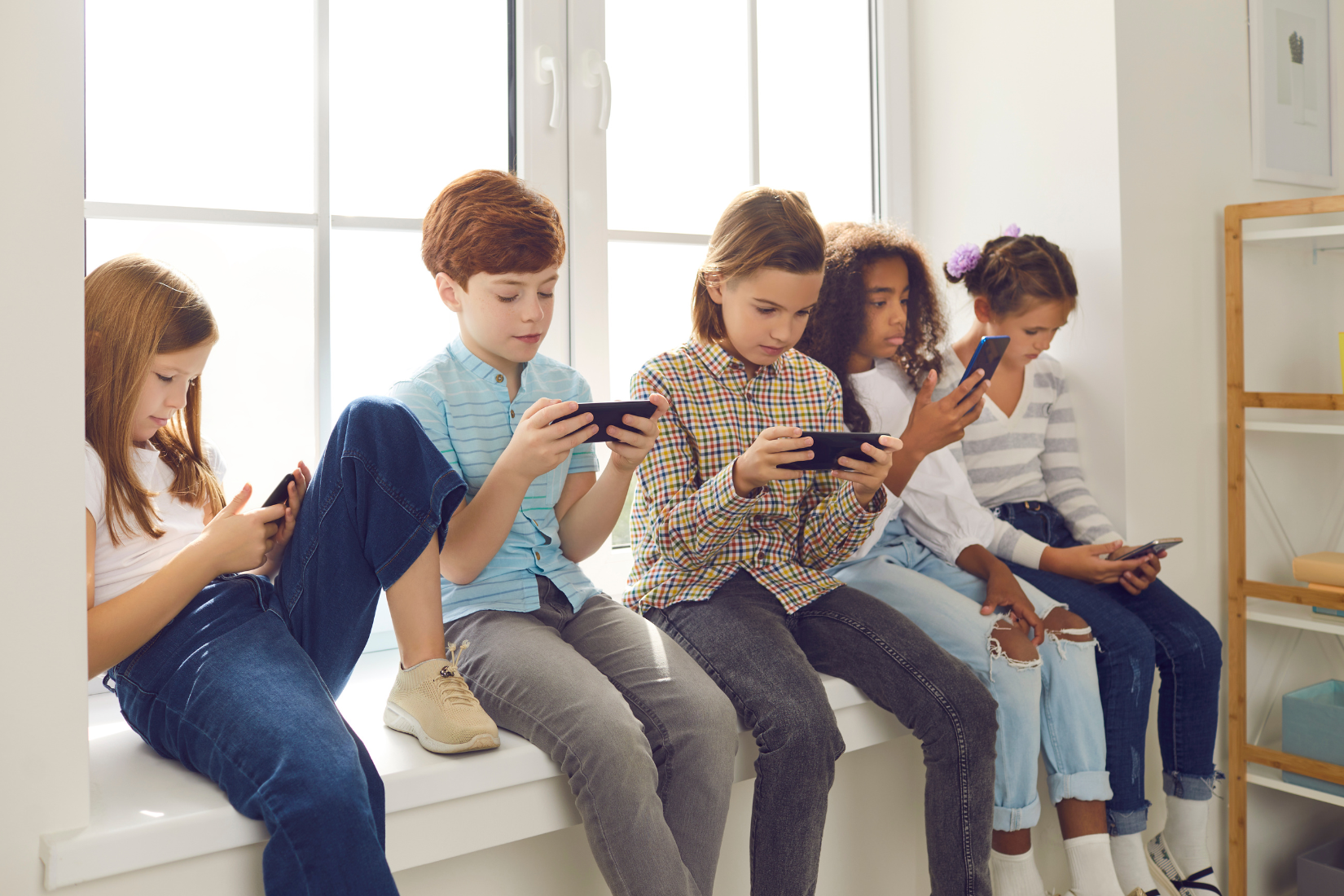 A diverse group of Gen Z and Gen Alpha youth sitting on a windowsill, all engrossed in their smartphones, representing the audience for viral meme culture.