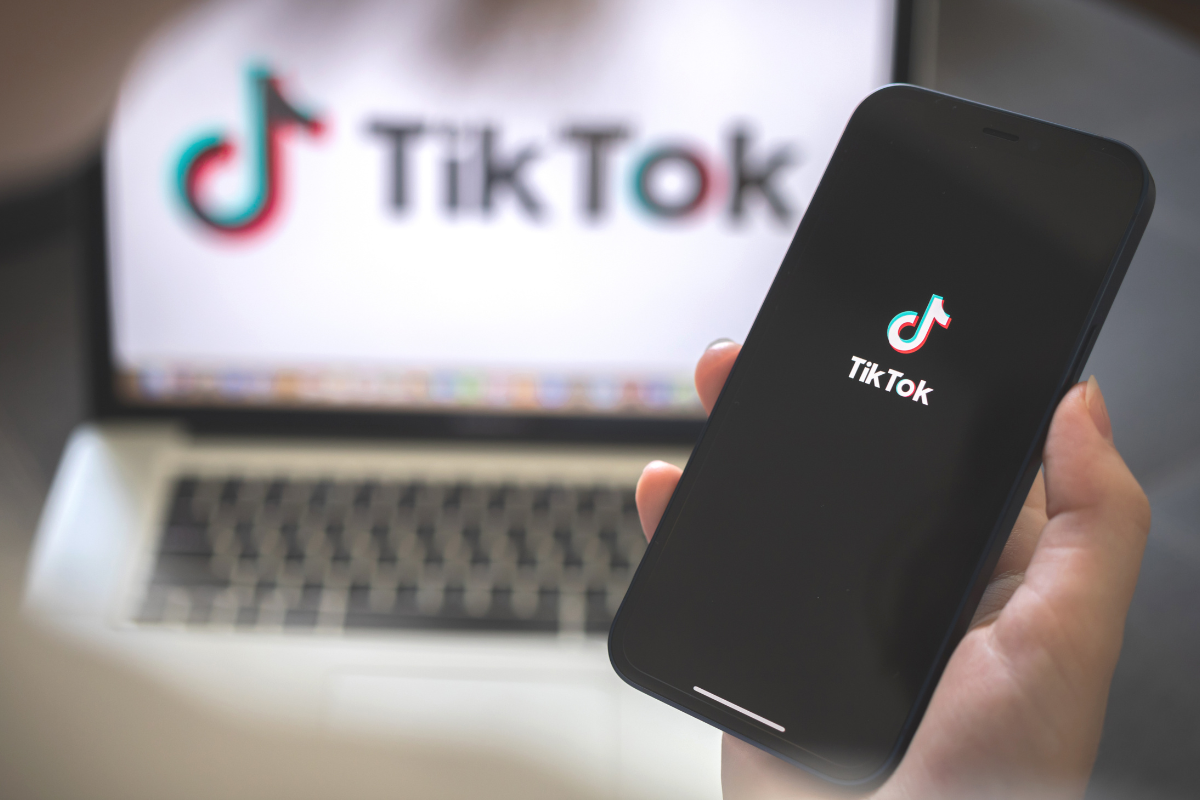 Hand holding a mobile phone with the TikTok logo, illustrating social media engagement, Influencer Marketing campaigns, and the latest TikTok trends used by a tiktok creator."
